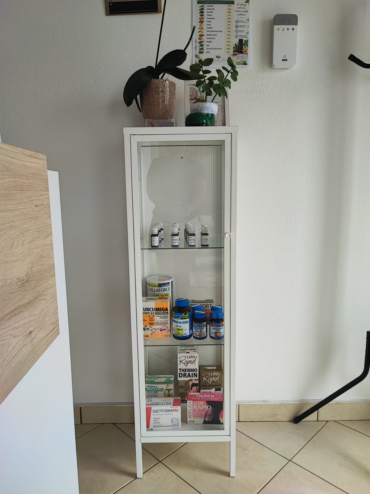 Vitrine com óleos essenciais e suplementos, encimada por plantas